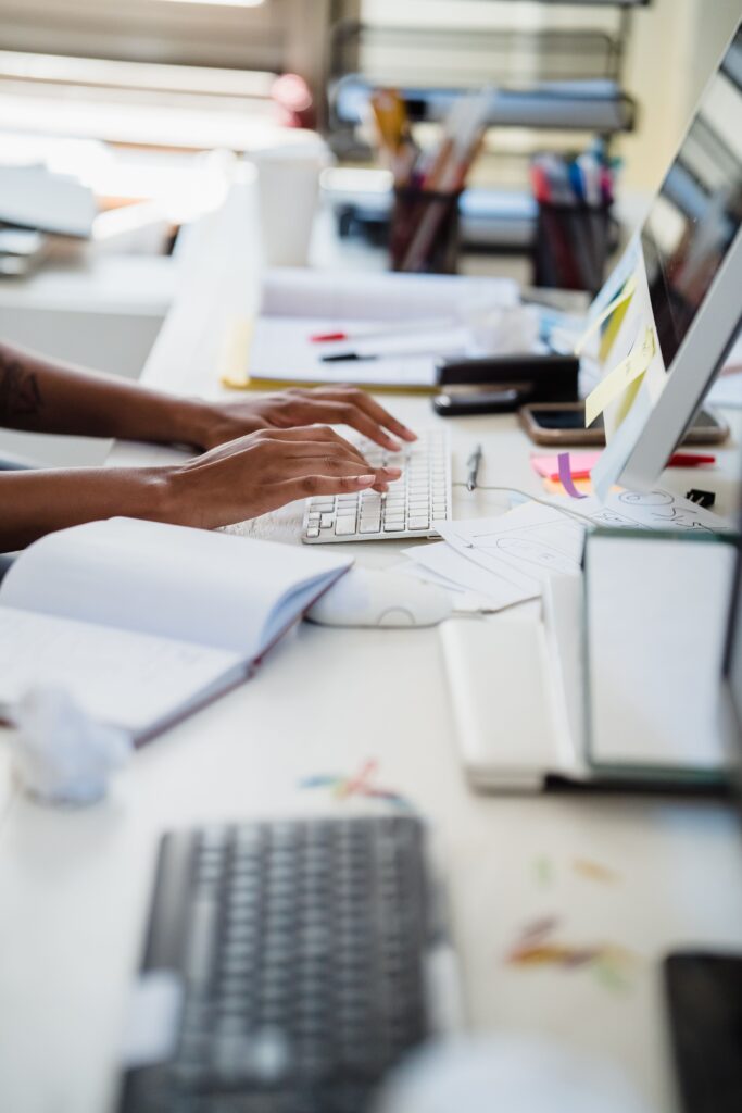 Close-up of hands typing on a white keyboard in a modern office setting.